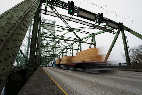 A logging truck drives on the Interstate 5 bridge between Oregon and Washington