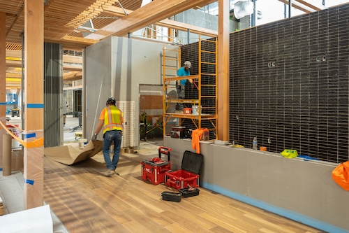 A scene of construction at Portland International Airport, with workers making finishing touches like installing flooring and furniture