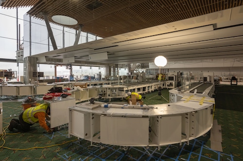 A scene of construction at Portland International Airport, with workers making finishing touches like installing flooring and furniture