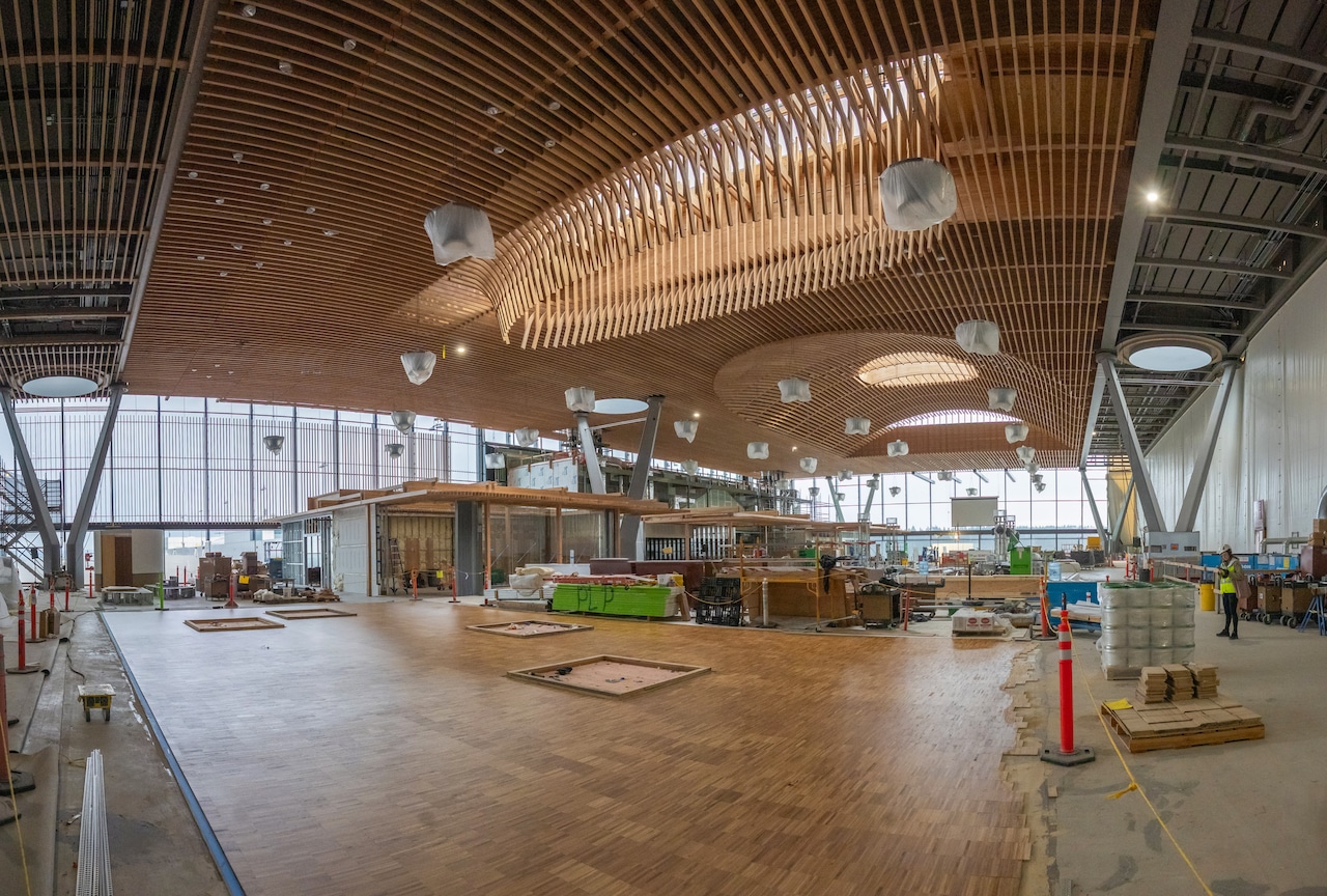 A scene of construction at Portland International Airport, with workers making finishing touches like installing flooring and furniture