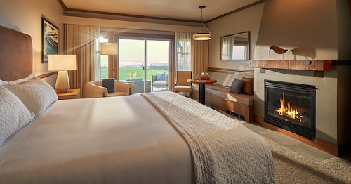 A guest room with a king bed, a fireplace and seating area with ocean views