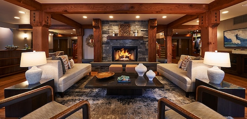 A common room with exposed timber beams, a large fireplace and couches