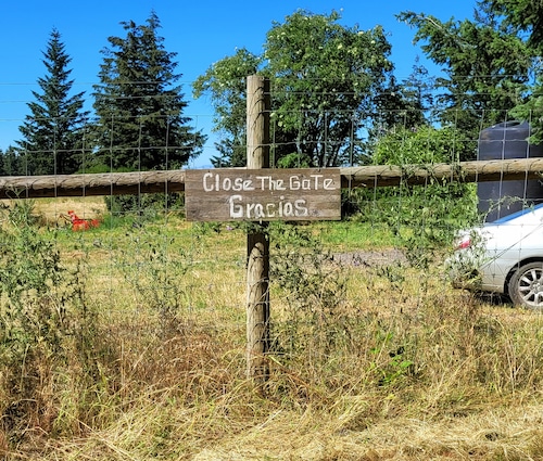 A wooden sign on a gate asks visitors to close the gate.