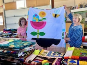 Dawn Boyd (left), executive director, and Jean Wells, founder of Sister Outdoor Quilt Show, display Aimee Hobson's quilt, "Flower Stack on a Cranky Crow."