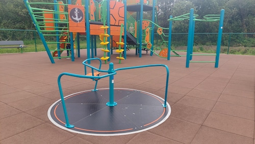 A play structure and merrygoround at Anchor Street Park and Playground