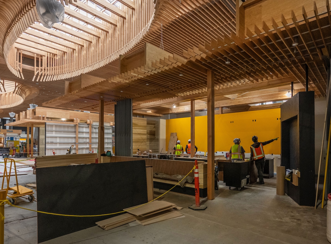 A scene of construction at Portland International Airport, with workers making finishing touches like installing flooring and furniture