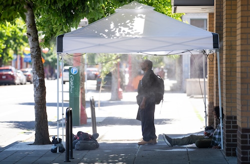 People use a misting tent to stay cool on a bright sunny day